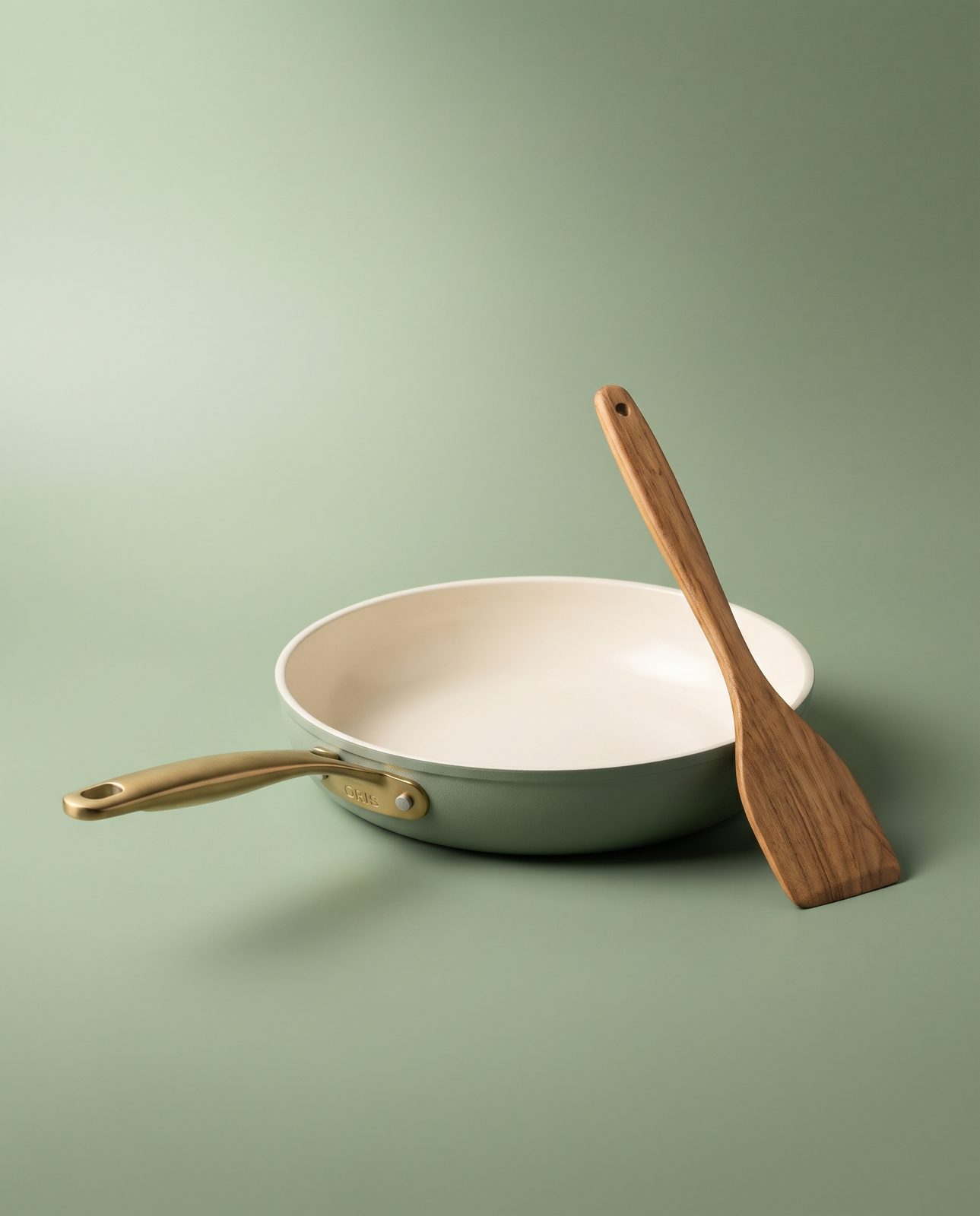 AI-generated after: sage ORIS skillet with wooden spatula on matching studio backdrop